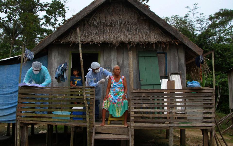 Maria Castro de Lima, 72, receives a dose of the Oxford-AstraZeneca COVID-19 vaccine from a healthcare worker, while sitting on the porch of her home in the Recanto community, along the Purus River - AP Photo/Edmar Barros