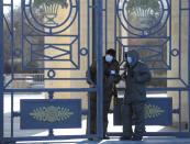 Security guards wearing protective masks stand near the gate of a park in Moscow