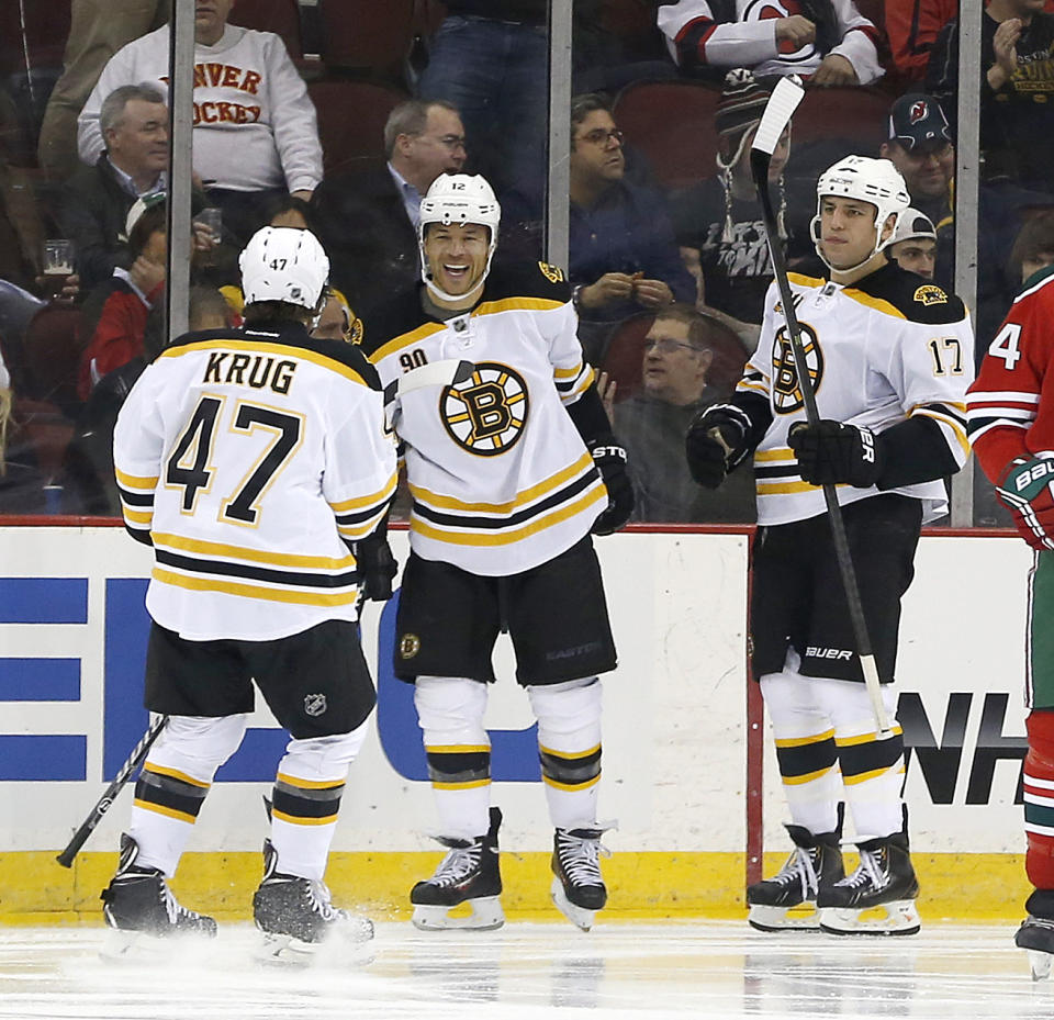 Boston Bruins defenseman Torey Krug (47), right wing Jarome Iginla (12) and left wing Milan Lucic (17) celebrate a goal by Iginla against the New Jersey Devils during the second period of an NHL hockey game, Tuesday, March 18, 2014, in Newark, N.J. (AP Photo/Julio Cortez)