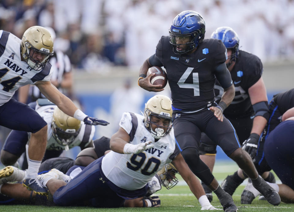 Air Force quarterback Haaziq Daniels, right, evades Navy defensive lineman Donald Berniard Jr., center, and linebacker Colin Ramos for a short gain in the second half of an NCAA college football game Saturday, Oct. 1, 2022, at Air Force Academy, Colo. (AP Photo/David Zalubowski)