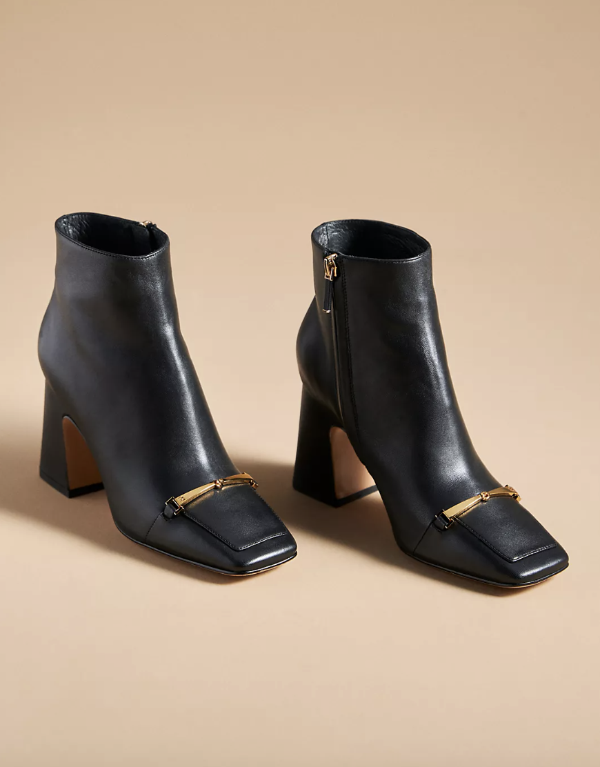 Lola Cruz Gorges Boots black heeled boots with gold bow embellishments (Photo via Anthropologie)