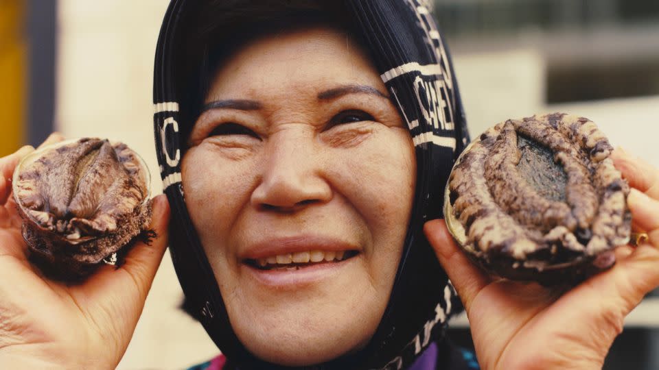 A woman holds fresh abalone, a historic delicacy in Korea. - Peter Ash Lee