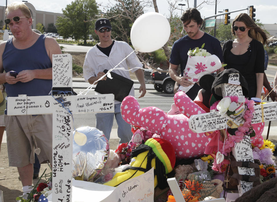 Actor Christian Bale and his wife Sibi Blazic, at right, carry flowers to place on a memorial to the victims of Friday's mass shooting, Tuesday, July 24, 2012, in Aurora, Colo. Twelve people were killed when a gunman opened fire during a late-night showing of the movie "The Dark Knight Rises," which stars Bale as Batman. (AP Photo/Ted S. Warren)