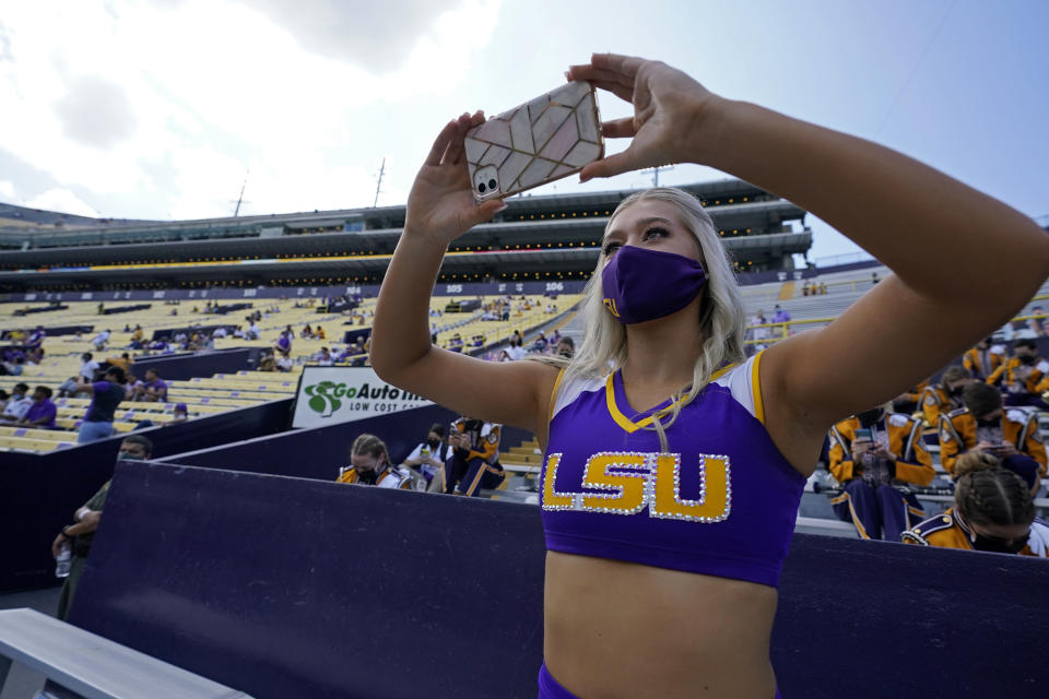 Aubree Lavergne, a member of the LSU Tiger Girl dance team, takes a photo wearing a mask due to COVID-19 restrictions, requiring social distancing and masks, before an NCAA college football game between the LSU and the Mississippi State in Baton Rouge, La., Saturday, Sept. 26, 2020. (AP Photo/Gerald Herbert)