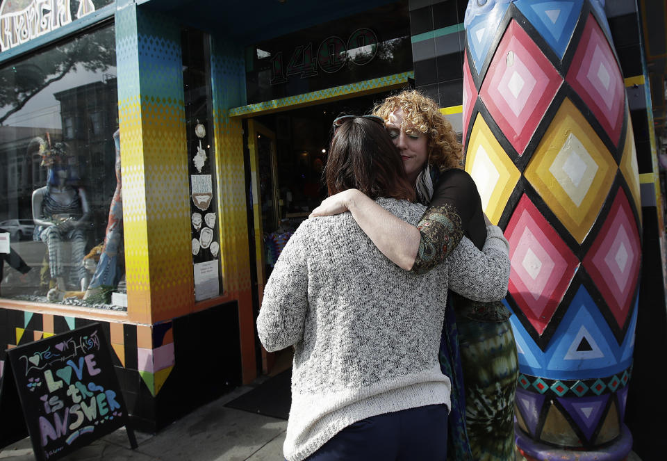 In this Oct. 1, 2018 photo, Sunshine Powers, owner of the store Love on Haight, right, hugs Christin Evans, owner of The Booksmith, outside of Powers' store in San Francisco. A measure on San Francisco's Nov. 6 ballot would levy an extra tax on hundreds of the city's wealthiest companies to raise $300 million for homelessness and mental health services. It's the latest battle between big business and social services advocates who say that companies such as Amazon, Google and Salesforce can afford to help solve severe inequities caused by business success. (AP Photo/Jeff Chiu)