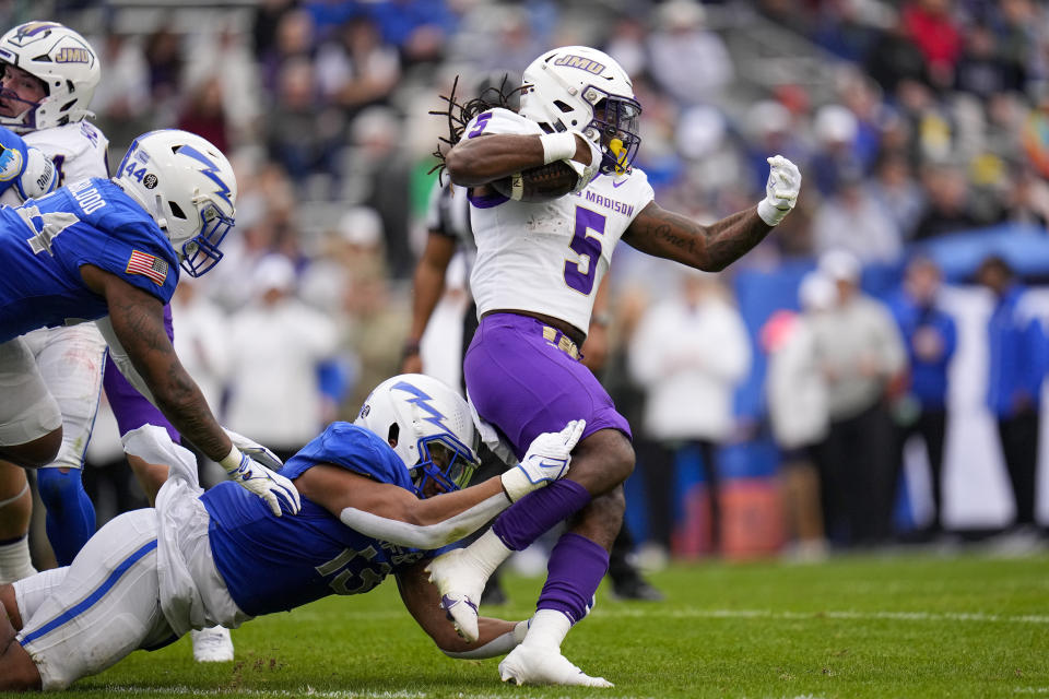 Air Force safety Jalen Mergerson, bottom, trips up James Madison running back Latrele Palmer (5) on a run during the first half of the Armed Forces Bowl NCAA college football game, Saturday, Dec. 23, 2023, in Fort Worth, Texas. (AP Photo/Julio Cortez)