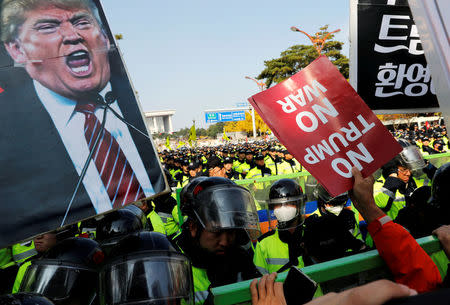 Anti-Trump protesters hold up signs in front of police officers near the South Korean National Assembly where U.S. President Donald Trump made a speech, in Seoul, South Korea, November 8, 2017. REUTERS/Kim Kyung-Hoon