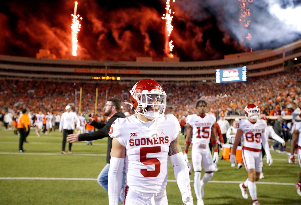 Oklahoma players walks off the field at fans begin to rush the field following a Bedlam college football game between the Oklahoma State University Cowboys (OSU) and the University of Oklahoma Sooners (OU) at Boone Pickens Stadium in Stillwater, Okla., Saturday, Nov. 27, 2021. OSU won 37-33.