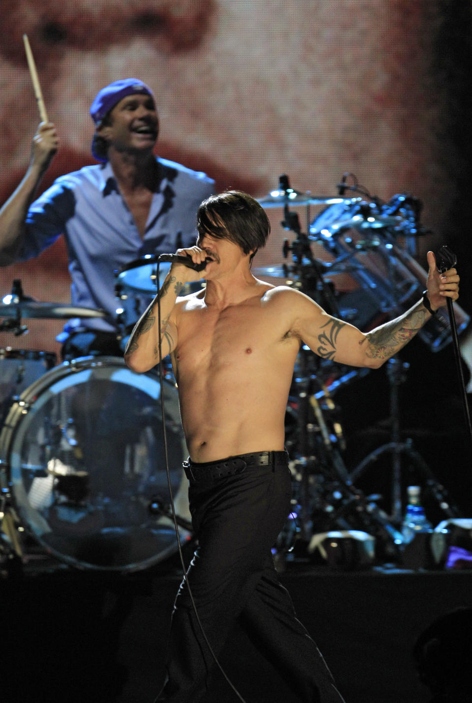 Red Hot Chili Peppers' Anthony Kiedis performs with drummer Chad Smith, background after induction into the Rock and Roll Hall of Fame Sunday, April 15, 2012, in Cleveland. (AP Photo/Tony Dejak)