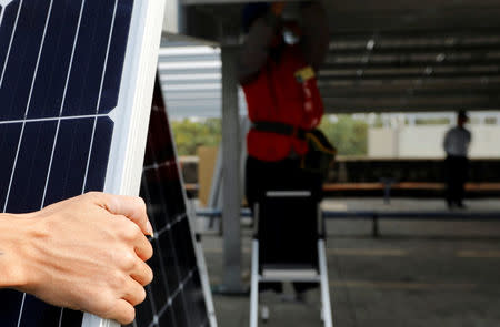 A prisoner (C) places solar panels on the roof of Pingtung Prison in Pingtung, Taiwan February 15, 2017. REUTERS/Tyrone Siu