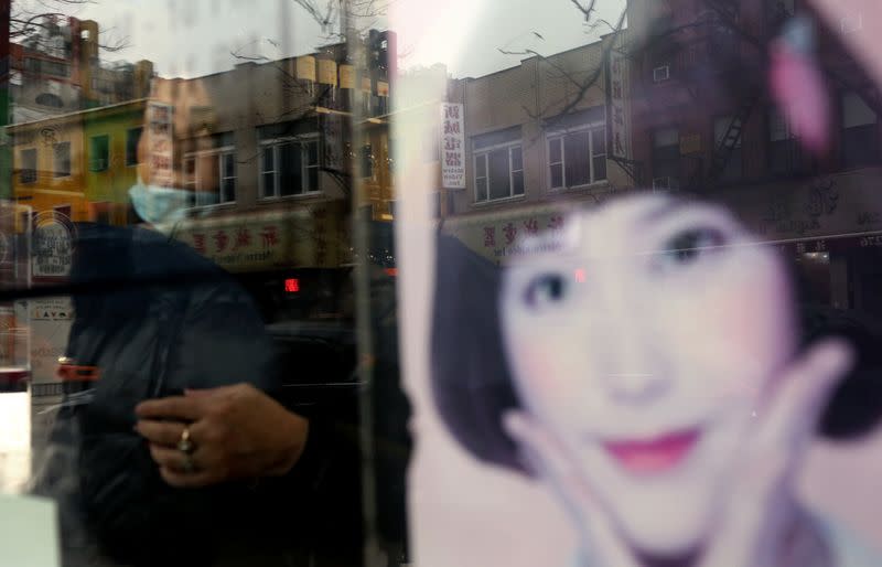 A woman who prefers to remain anonymous looks through a window in Chinatown in New York