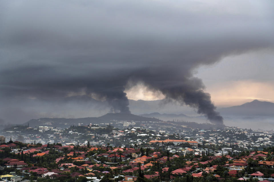 FILE - Smoke rises during protests in Noumea, New Caledonia, Wednesday May 15, 2024. France has imposed a state of emergency in the French Pacific territory of New Caledonia. The French prosecutor for New Caledonia says there's been another shooting death in the riot-hit French Pacific territory, with a police officer taken into custody after using their firearm Friday May 24, 2024 when they were set upon by a group of about 15 people. It comes a day after French President Emmanuel Macron made an emergency round-trip from Paris to de-escalate the violence in New Caledonia where Indigenous Kanak people have long sought independence from France. (AP Photo/Nicolas Job, File)