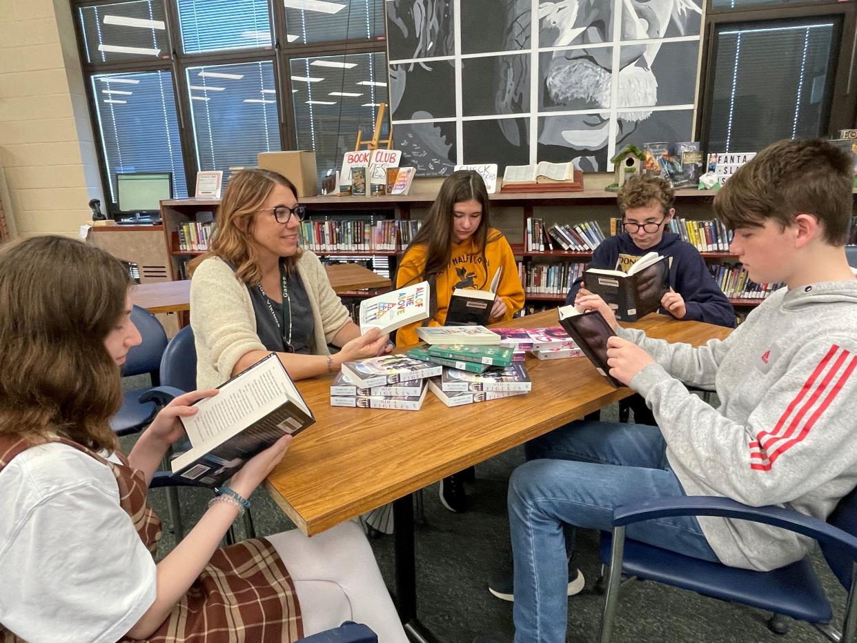 Kim Garee, English college composition, library and research teacher for Northridge Local Schools, looks at the new books the district received from the Mathical Book Prize with 8th graders Allison Roberts, Brant Stockburger and Simon Tornichio, and junior Ava McBride.