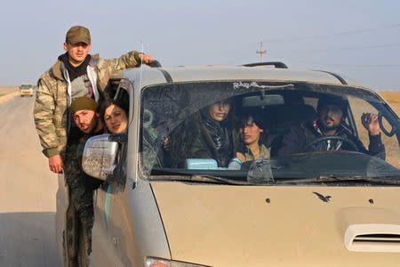 Kurdish fighters ride in a vehicle on the highway connecting the Iraqi-Syrian border town of Rabia and the town of Snuny, north of mount Sinjar December 20, 2014. REUTERS/Massoud Mohammed