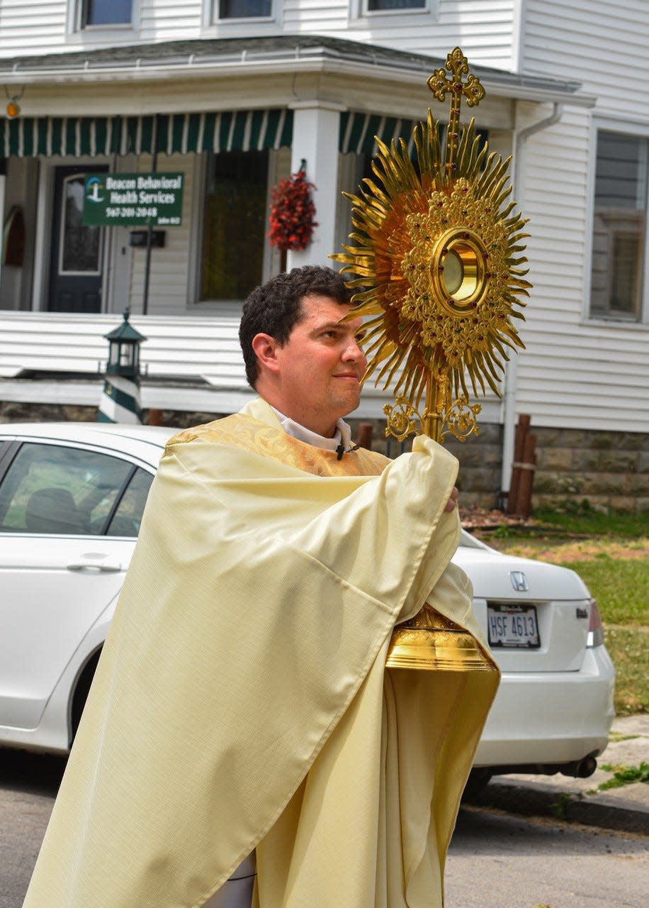 The Rev. Matt Frisbee carries the consecrated host in a monstrance throughout Fremont on Sunday. The event, he said, helped the church “bring Christ into the streets.”