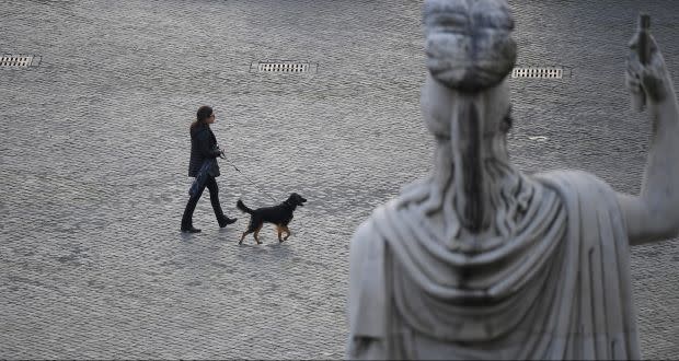 A woman walks her dog in Rome.