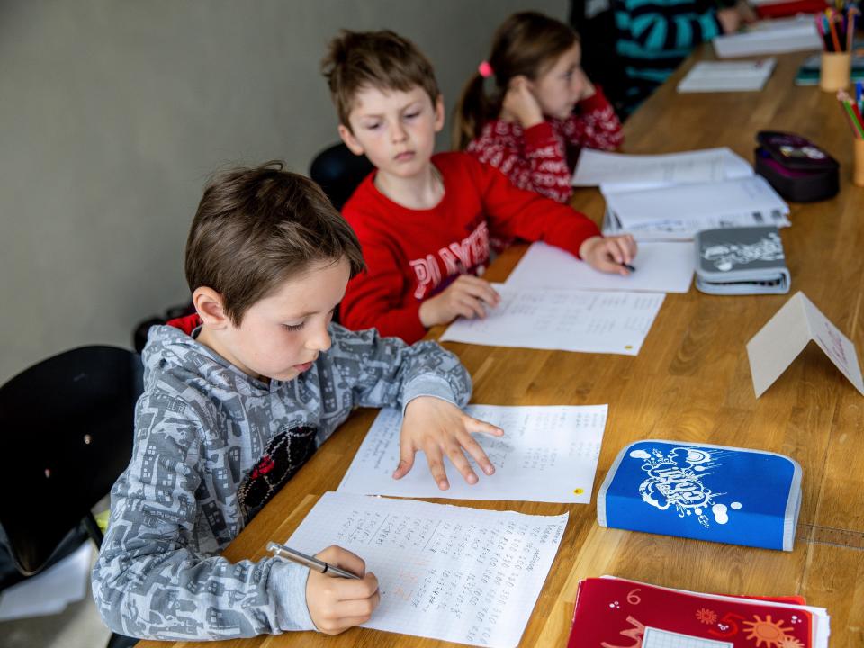 Two boys work on school work at a desk.