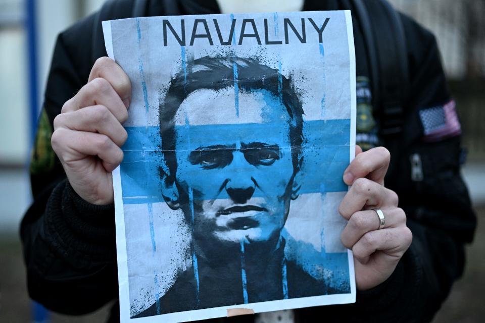 A demonstrator in Warsaw, Poland, carries a placard with a picture of late Russian opposition leader Alexei Navalny as people gather to attend a rally in front of the Russian Embassy there on Feb. 16, 2024.