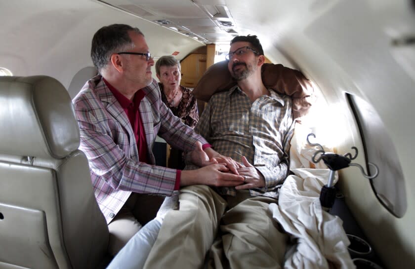 In this July 11, 2013 file photo, Jim Obergefell, left and John Arthur, right, are married by officiant Paulette Roberts, rear center, in a plane on the tarmac at Baltimore/Washington International Airport in Glen Burnie, Md. Federal Judge Timothy Black on Wednesday, Dec. 18, 2013, questioned the constitutionality of Ohio's ban on gay marriage and whether state officials have the authority to refuse to recognize the marriages of gay couples who wed in other states. Black earlier ruled in favor of the couple in a lawsuit seeking to recognize the couples' marriage on Arthur's death certificate before he died in October from ALS. (AP Photo/The Cincinnati Enquirer, Glenn Hartong, File) MANDATORY CREDIT, NO SALES