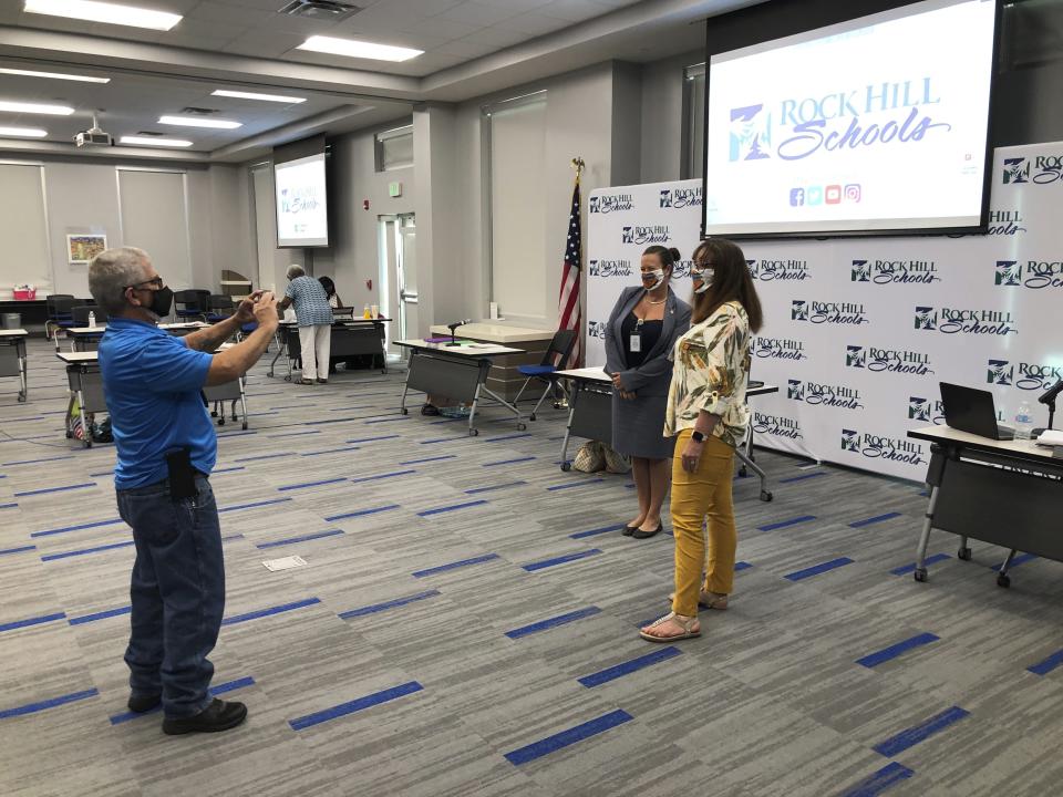 Rock Hill School Board member Terry Hutchinson takes a picture of board chairwoman Helena Miller, left, and Windy Cole, right, in their matching masks during a break at the board's meeting in Rock Hill, South Carolina, on Monday, Aug. 10, 2020. Like school boards across the nation, Rock Hill's board has had to answer the simple question when do children return to school with no easy or guaranteed safe answer. (AP Photo / Jeffrey Collins)