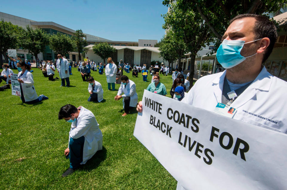 People kneel as doctors, nurses and other health care workers participate in a "White Coats for Black Lives" event in solidarity with George Floyd and other black Americans killed by police officers, at the Queen of the Valley Hospital in West Covina, California on June 11, 2020.<span class="copyright">Mark Ralston—AFP/Getty Images</span>