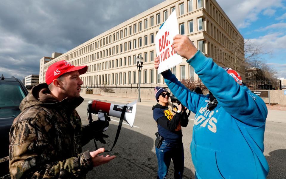 Supporters of Donald Trump (L) and a supporter of President-Elect Joe Biden argue as the Board of State Canvassers vote to certify the election in Lansing, Michigan - AFP