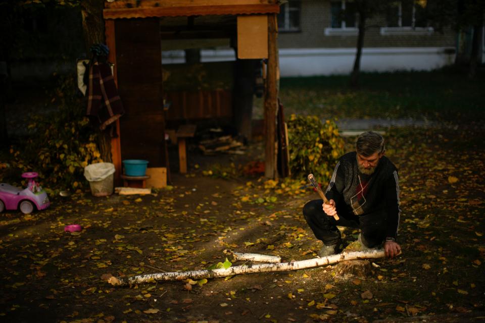 A local man cuts pieces of firewood in Kivsharivka, Ukraine, Sunday, Oct. 16, 2022. As temperatures drop below freezing in eastern Ukraine, those who haven't fled from the heavy fighting, regular shelling, and months of Russian occupation are now on the threshold of a brutal winter and digging in for the cold months.