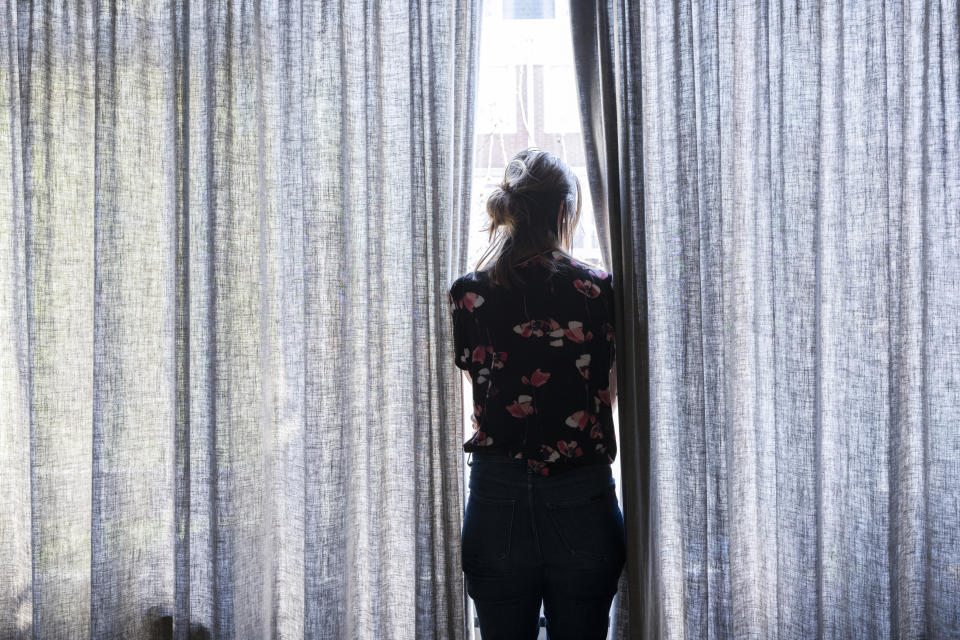 lonely woman looking out the window during quarantine