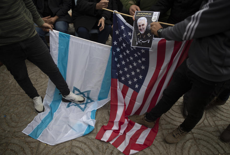 Palestinians step on US and Israeli flags as they attend a mourning house held by Palestinian factions for Qassem Soleimani, the Iran's head of the Quds Force, who was killed in a US drone strike early Friday, in Gaza City, Saturday, Jan 4, 2020. (AP Photo/Khalil Hamra)