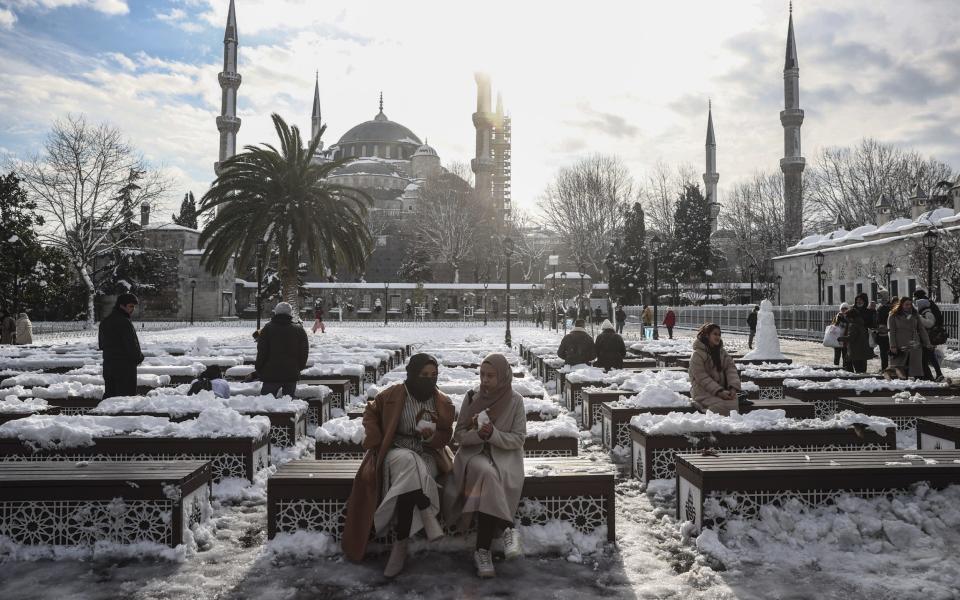 People sit on the benches around Sultanahmet square after snowfall in Istanbul - Anadolu Agency 