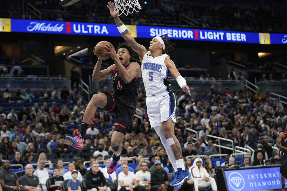 Toronto Raptors' Scottie Barnes (4) gets past Orlando Magic's Paolo Banchero (5) for a shot during the first half of an NBA basketball game Friday, Dec. 9, 2022, in Orlando, Fla. (AP Photo/John Raoux)