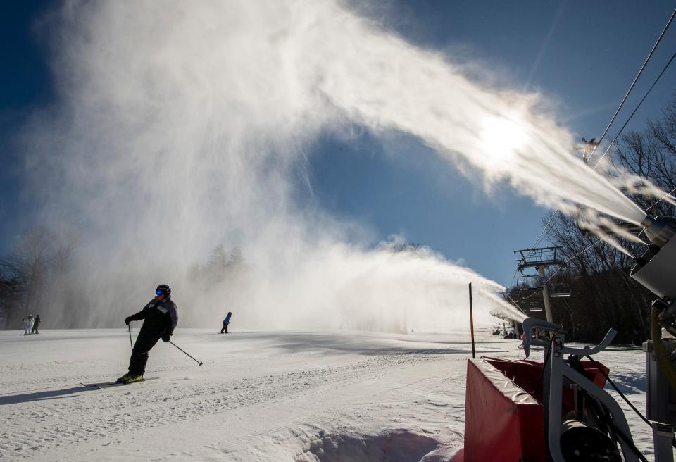 Skiers pass a row of snowmaking machines at Wachusett Mountain Ski Area.