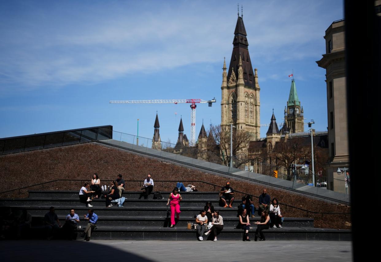 People take advantage of the warm weather at the Bank of Canada plaza in downtown Ottawa on Tuesday. (Sean Kilpatrick/The Canadian Press - image credit)