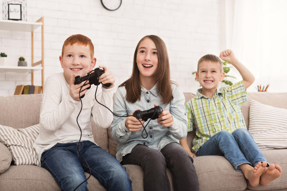 Three kids playing video games on the couch