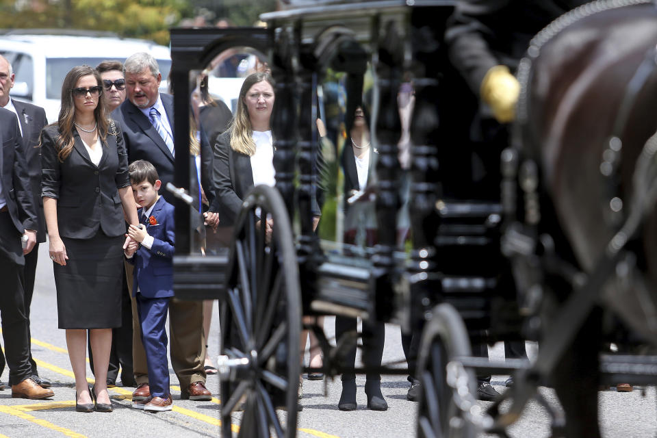 Edwin Edwards' wife Trina and son Eli, 7, watch as the horse-drawn carriage carrying the former Louisiana Governor arrives at the Old State Capitol building following a processional through the streets of Baton Rouge, La., Sunday, July 18, 2021. The processional featuring a law enforcement motorcade as well as the Southern University Marching Band and ended at the Old State Capital building where a private funeral service was held. The colorful and controversial four-term governor died of a respiratory illness on Monday, July 12th at the age of 93. (AP Photo/Michael DeMocker)