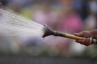 A stadium employee waters the court after Poland's Iga Swiatek defeated Alison Riske of the U.S. in their second round match of the French Open tennis tournament at the Roland Garros stadium Thursday, May 26, 2022 in Paris. Swiatek won 6-0, 6-2. (AP Photo/Michel Euler)