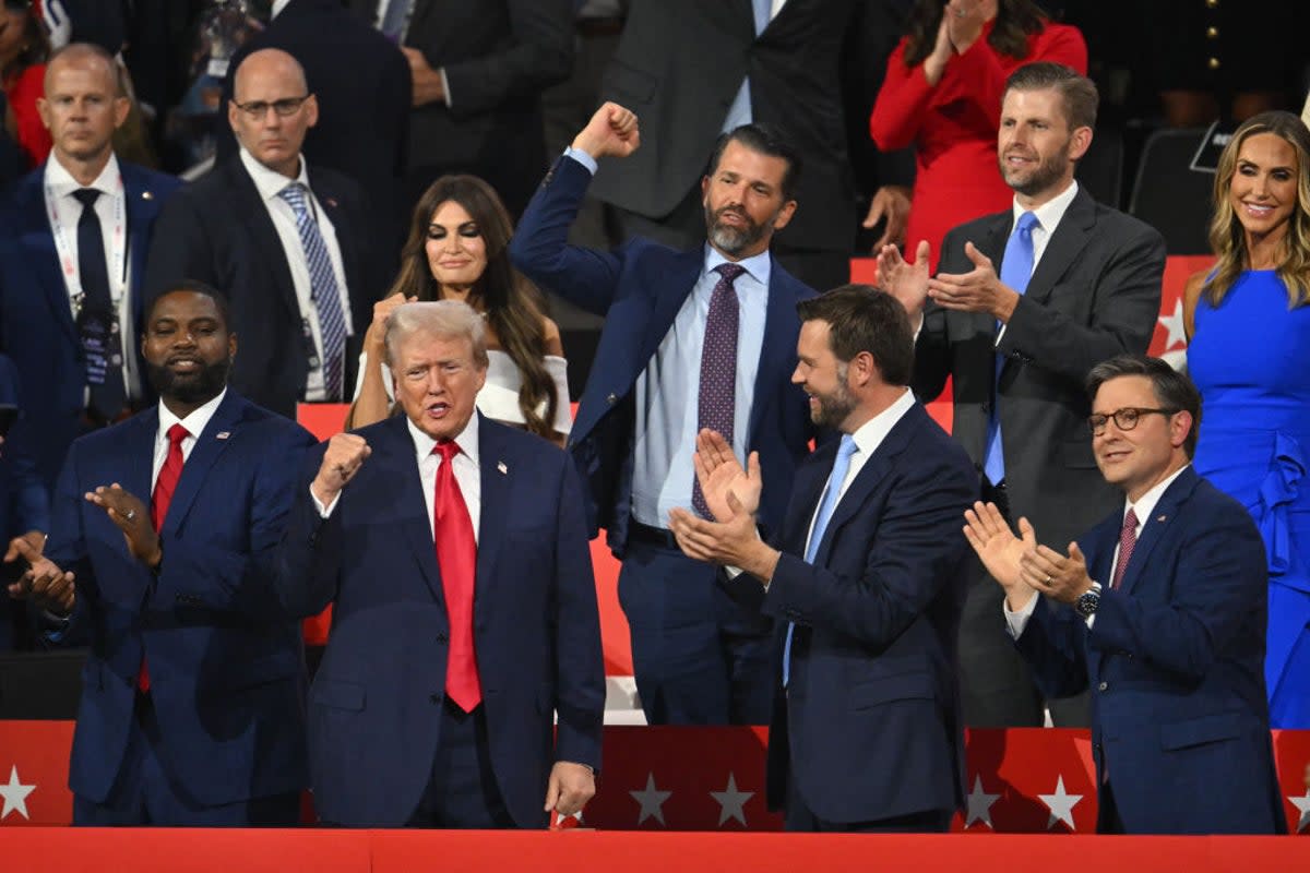 Donald Trump raises a fist during day one of the Republican National Convention in Milwaukee. In the row behind him stand four of his family members; from left to right, Kim Guilfoyle, husband Donald Trump Jr, Eric Trump Jr and his wife, RNC co-chair Lara Trump. (AFP via Getty Images)