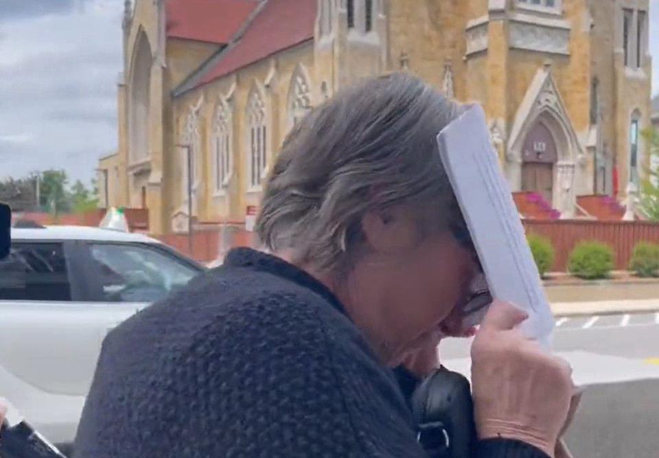 Denise Lodge, 63, of Goffstown, New Hampshire, shields her face from reporters as she leaves a New Hampshire court on Wednesday, June 14, 2023 to face charges in connection with trafficking body parts stolen from the Harvard Medical School morgue, where her husband, Cedric Lodge, formerly worked as morgue manager, prosecutors say.