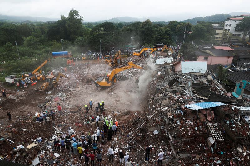 Rescue workers search for survivors in the debris after a five-story building collapsed in Mahad