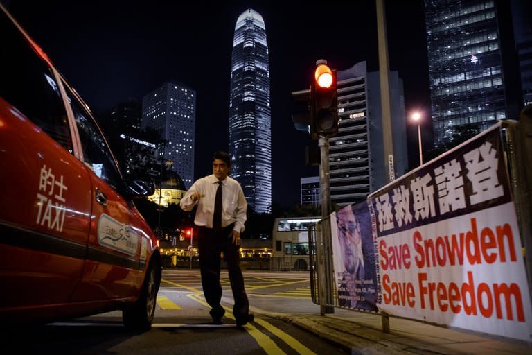 A man crosses a street next to banner displayed in support of former US spy Edward Snowden, in Hong Kong, on June 17, 2013. The Sunday Morning Post said the 30-year-old Snowden remained "safe" in Hong Kong and had not been detained by police after he was charged in the United States with theft and espionage