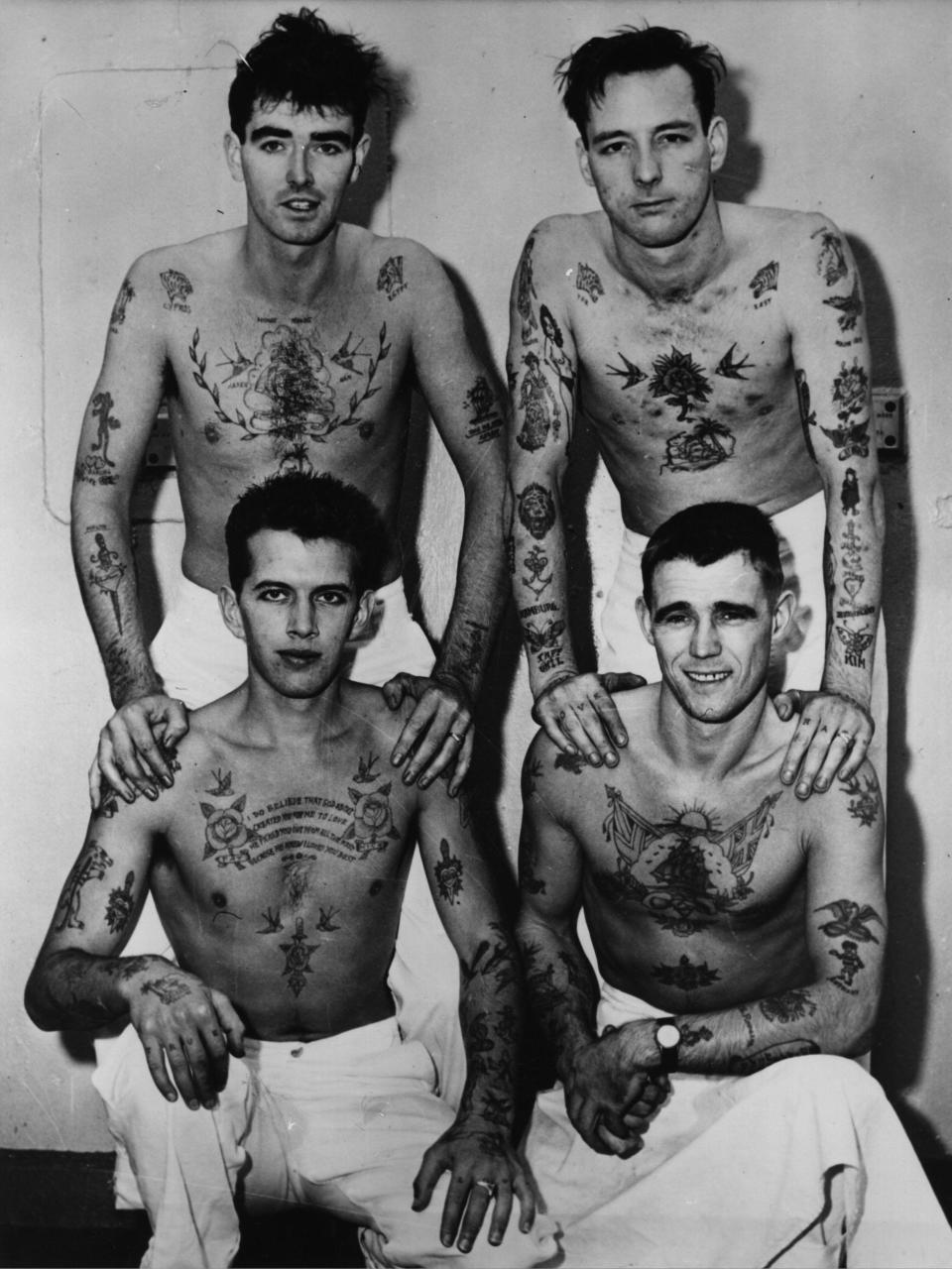 Four men who work as cooks aboard the HMS Belfast show off their tattoos.