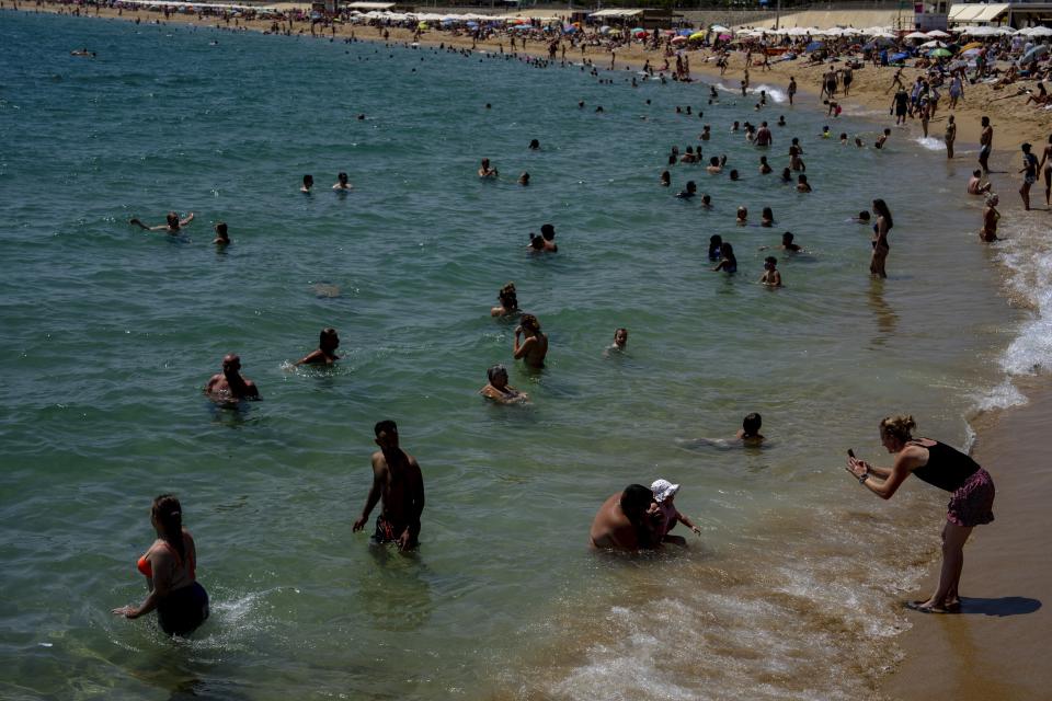 FILE - People cool off on a beach in Barcelona, Spain, Aug. 9, 2023. The latest calculations from several science agencies Friday, Jan. 12, 2024, all say that global average temperatures for 2023 shattered existing heat records. (AP Photo/Emilio Morenatti)