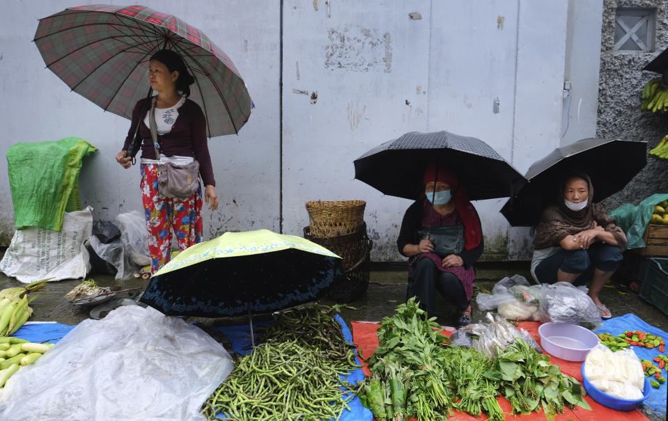 Naga women hold umbrellas and wait selling vegetables by a road in Kohima, capital of the northeastern Indian state of Nagaland, Wednesday, June 17, 2020. Kohima, the semi-urban capital of the northeastern state of Nagaland, relies on satellite villages for green vegetables. But supply lines were cut during India’s 10-week nationwide lockdown, inspiring residents to grow their own. (AP Photo/Yirmiyan Arthur)