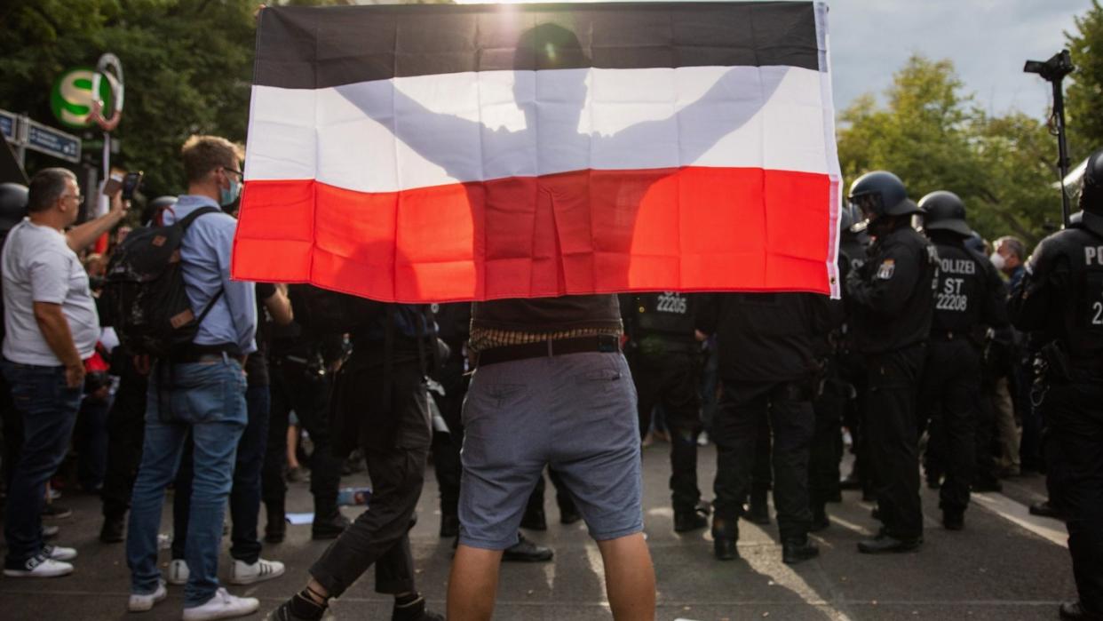 Ein Mann hält eine Reichsflagge bei einem Protest gegen die Corona-Maßnahmen vor der russischen Botschaft.