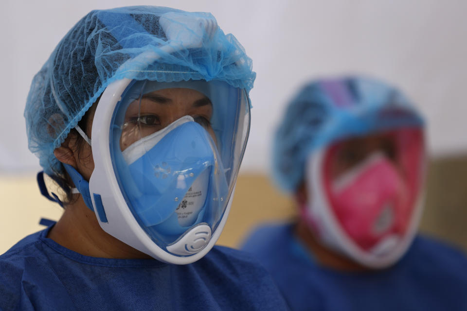 FILE - In this July 24, 2020 file photo, Dr. Diana Pacheco, left, and nurse Claudia Flores Martinez prepares to attend to their next patient, as they conduct COVID-19 testing inside a mobile diagnostic tent, in San Gregorio Atlapulco in the Xochimilco district of Mexico City, Friday, July 24, 2020. The city of about 10 million — with another 10 million living in the surroundings — is now testing about 4,000 people a day. (AP Photo/Rebecca Blackwell, File)