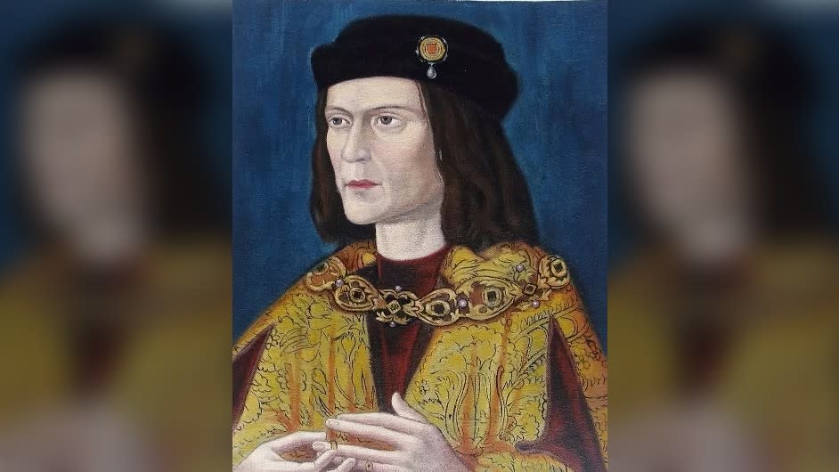 Portrait of King Richard III of England, painted c. 1520. He has pale skin and has shoulder-length brown hair. He's wearing a black hair with a gold emblem on it. He's also wearing red and gold robes.