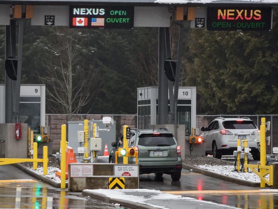 A motorist scans a NEXUS card as another speaks with a Canada Border Services Agency officer at a primary inspection booth at the Douglas-Peace Arch border crossing in Surrey, B.C., on Wednesday February 5, 2020.  (Darryl Dyck/The Canadian Press - image credit)