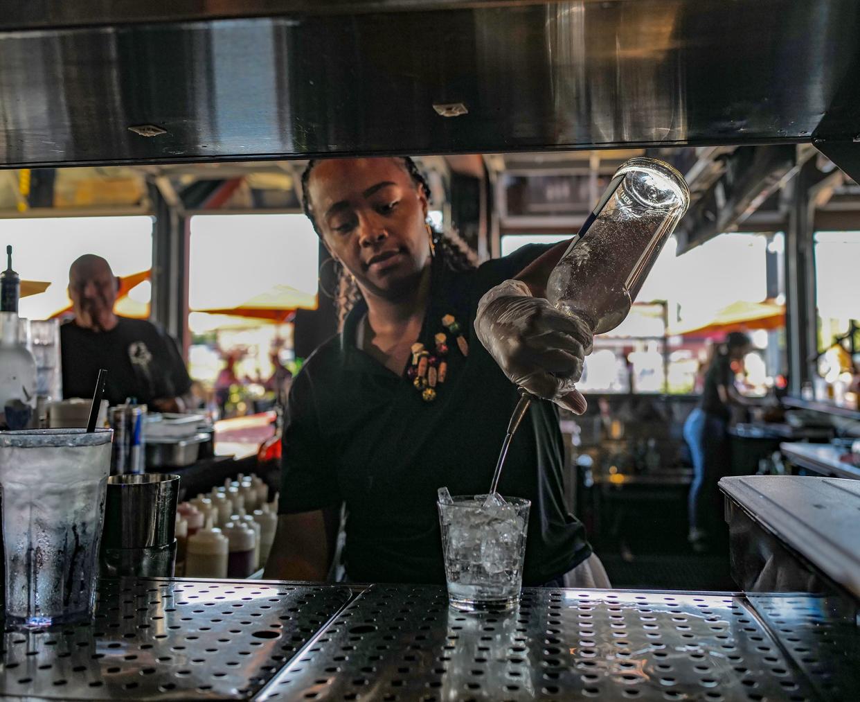 A bartender makes a drink on the covered outdoor patio bar at One North Kitchen and Bar in Delta Township on Aug. 10, 2023.
