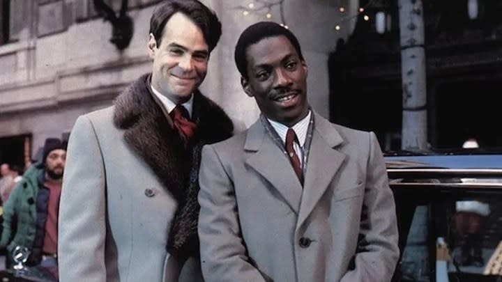 Dan Aykroyd and Eddie Murphy standing together in matching peacoats in a scene from Trading Places.
