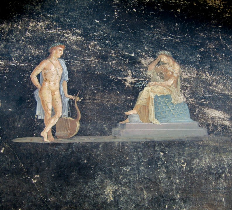 This image released by the Italian Culture Ministry on Wednesday, April 10, 2024, shows a fresco depicting the Greek mythology’s figures Cassandra, right, a cursed prophetess, and Apollo, God of oracles and knowledge, inside an imposing banquet hall, with elegant black walls, decorated with mythological subjects inspired by the Trojan War, recently unhearted in the Pompeii archaeological area near Naples in southern Italy. (Italian Culture Ministry via AP, HO)